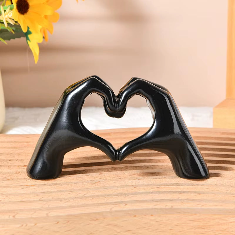 Black-finish heart hand sculpture on a wooden surface